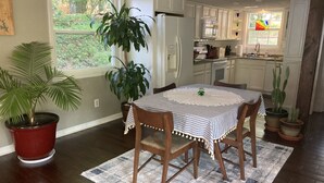A dining area with a table set for two, surrounded by wooden chairs, a potted plant, and a patterned rug. - Lakefront cottage on rustic setting in cove (Buckhead)