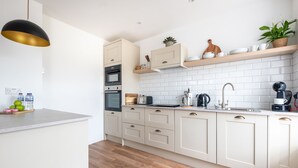 Eine moderne Küche mit hellen Schränken, einer weißen Fliesenspiegel und Holzboden.