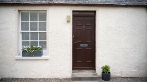 Ein weißes Gebäude mit einer braunen Tür und einem Fenster mit Blumenkasten.
