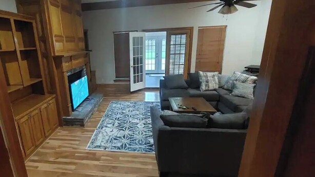Sala de estar com sofá, mesa de centro e lareira. Há um armário de madeira e uma televisão.