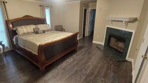 Quarto com uma cama grande, lareira e mesa de cabeceira.