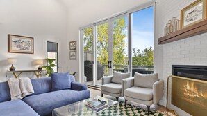 A modern living room with a blue sectional sofa, a glass coffee table, and a fireplace.