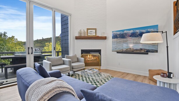 A modern living room with a fireplace, a large window, and a view of the outdoors.