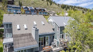 A multi-story house with a large deck, a covered patio, and a mountain view.