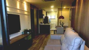Una sala de estar moderna con un televisor de pantalla plana, un sofá y un comedor con mesa y sillas.