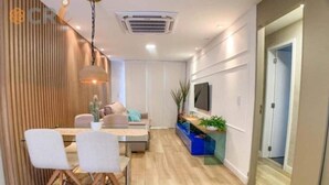 Una sala de estar moderna con comedor, televisor montado en la pared y piso de madera.