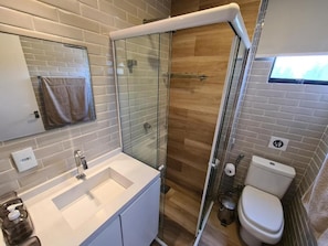A modern bathroom with a glass shower enclosure, a white sink, and a toilet. - Maresia Beach (Fortaleza)