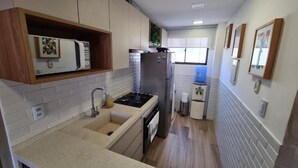 Una cocina compacta con microondas, estufa, lavaplatos y refrigerador.