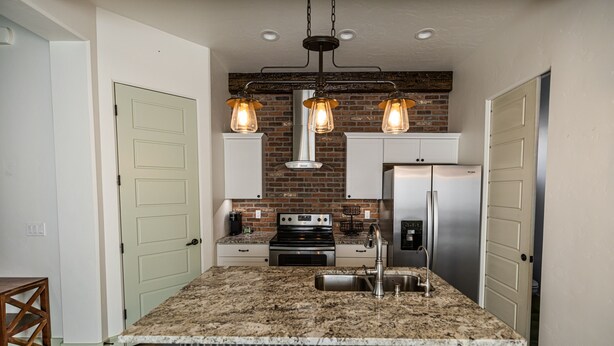 A kitchen with a granite island, stainless steel appliances, and a brick backsplash. - Modern Holistic Home - Near the Village & Shopping!  (Meridian)