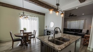 A kitchen with a central island, wooden dining table, and chairs. - Modern Holistic Home - Near the Village & Shopping!  (Meridian)