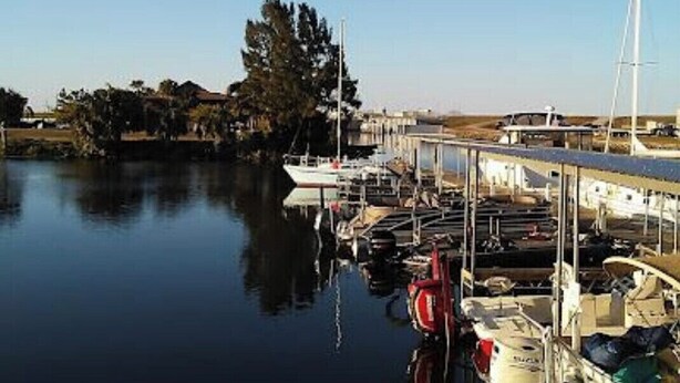 Un puerto deportivo con barcos amarrados, agua tranquila y cielo despejado.