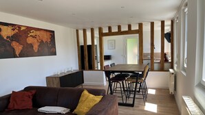 A modern living room with a brown leather sofa, a wooden dining table, and a large world map on the wall. - Casa Belavista, seine view and jacuzzi (Connelles)