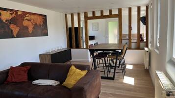 Un salon moderne avec un canapé en cuir marron, une table à manger en bois et une grande carte du monde accrochée au mur.