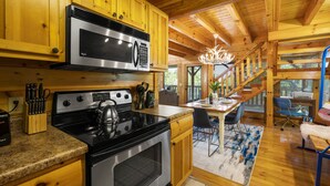 A kitchen with wooden cabinets, a stainless steel stove, and a microwave. - Modern Cabin w/ Hot Tub - 17 min to Dollywood (Sevierville)
