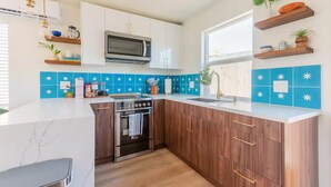 Una cocina moderna con armarios blancos, horno empotrado, microondas y pileta.