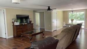 A living room with a sofa, a coffee table, a TV, and a ceiling fan. - We are located in the beautiful blue ridge mountains (Sparta)