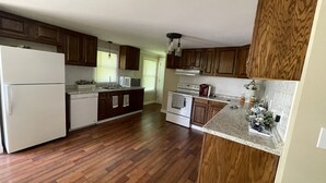 A kitchen with wooden cabinets, a white refrigerator, a microwave, a stove, and a dishwasher. - We are located in the beautiful blue ridge mountains (Sparta)