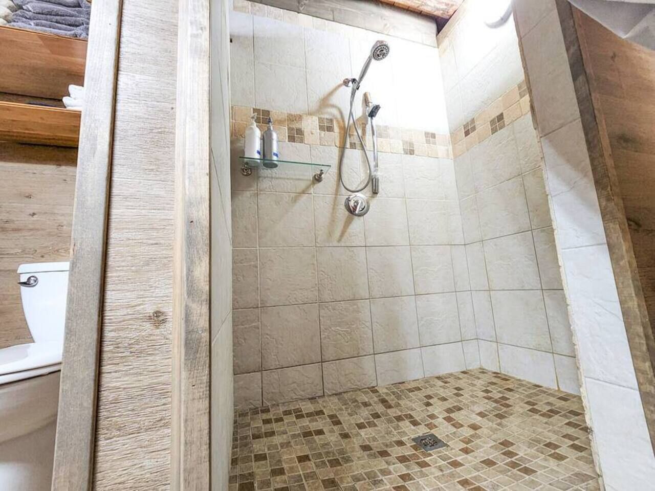 A shower area with a glass door, tiled walls, and a showerhead.