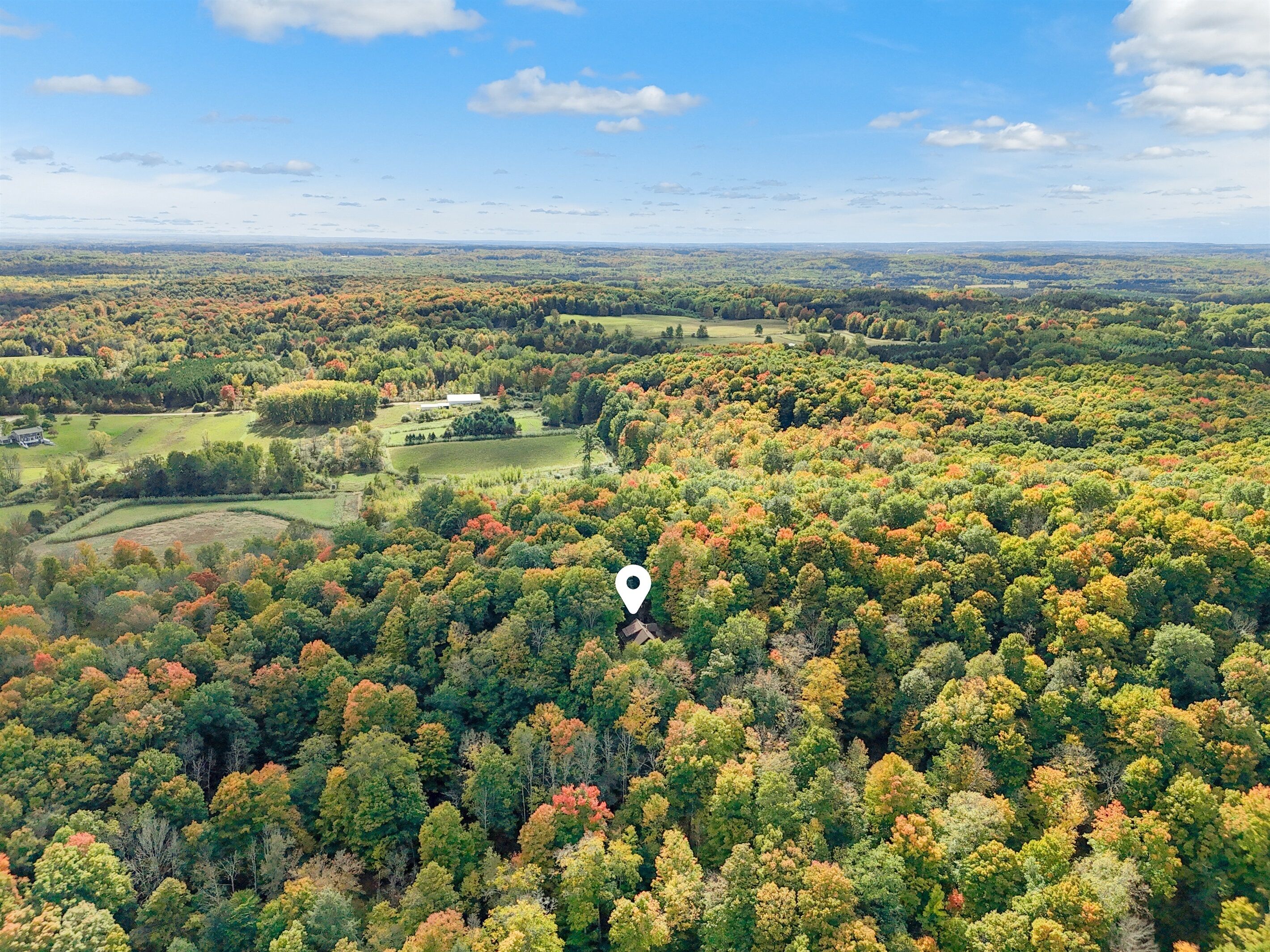 An aerial view of a forested area with a golf course and a building.