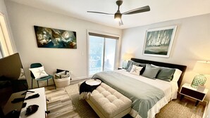 Une chambre d’hôtel moderne équipée d’un lit, d’un bureau, d’une chaise, d’un ventilateur de plafond et d’œuvres d’art accrochées aux murs.