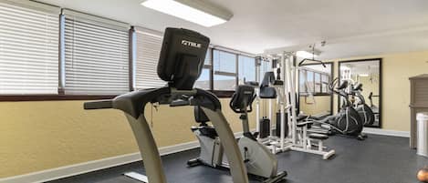 Un gimnasio con cintas de correr, máquinas de pesas y un espejo grande.
