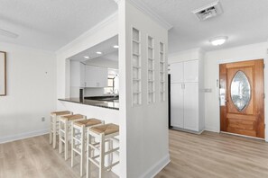 A modern kitchen with white cabinets, a built-in oven, and a wooden door with a glass panel. - Bright Oceanfront PH- Pools, Tiki Bar, Breakfast (North Myrtle Beach)