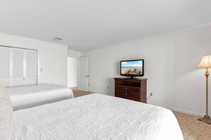 A hotel room with a large bed, a television on a wooden dresser, and a lamp.