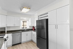 A kitchen with white cabinets, a black refrigerator, and a granite countertop.