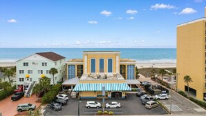 A hotel with a beach view, a parking lot, and a blue-striped awning.