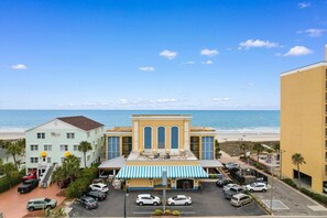A hotel with a beach view, a parking lot, and a blue-striped awning.
