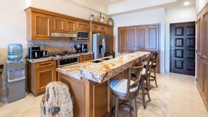 Eine moderne Küche mit Holzschränken, Granit Arbeitsplatten, einem Edelstahlkühlschrank und einem Wasserspender.