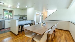 A modern kitchen with white cabinets, a wooden dining table, and white chairs.