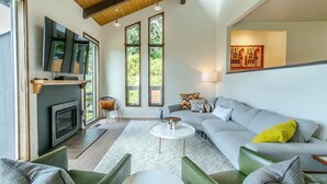 A modern living room with a fireplace, large windows, a sofa, and a coffee table.