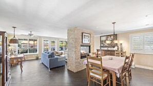 A spacious living area with a stone fireplace, dining table, and comfortable seating. - Cheerful Bedroom Beach Cottage  STR15-0264 (Dana Point)