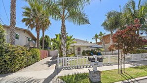 A residential street with houses, palm trees, and a white picket fence. - Cheerful Bedroom Beach Cottage  STR15-0264 (Dana Point)