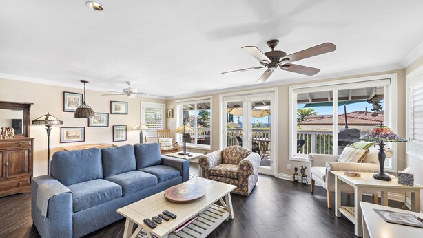 A spacious living room with a blue sofa, patterned armchair, and a dining table with a lamp. - Cheerful Bedroom Beach Cottage  STR15-0264 (Dana Point)