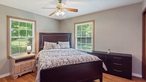 A bedroom with a bed, nightstands, a dresser, and a ceiling fan. - family home (Knoxville)