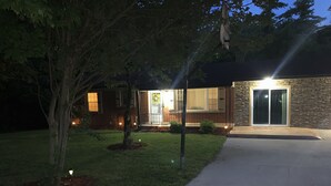 A residential house with a stone facade, a front porch, and a well-lit entrance. - family home (Knoxville)