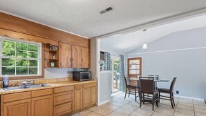 A kitchen with wooden cabinets, a microwave, and a dining area with a table and chairs. - family home (Knoxville)