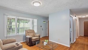 A spacious living room with a beige sofa, a recliner, and a glass coffee table. - family home (Knoxville)