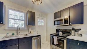 A modern kitchen with dark cabinetry, stainless steel appliances, and a window providing natural light.
