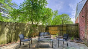 An outdoor patio with a wooden fence, a brick wall, and a table with four chairs.