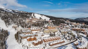 A snow-covered resort town with multiple buildings, including hotels and cabins, surrounded by dense forests and mountains. - Trapper's Lodge 4 Bd W/great View, Private Hot Tub (Beaverdell)