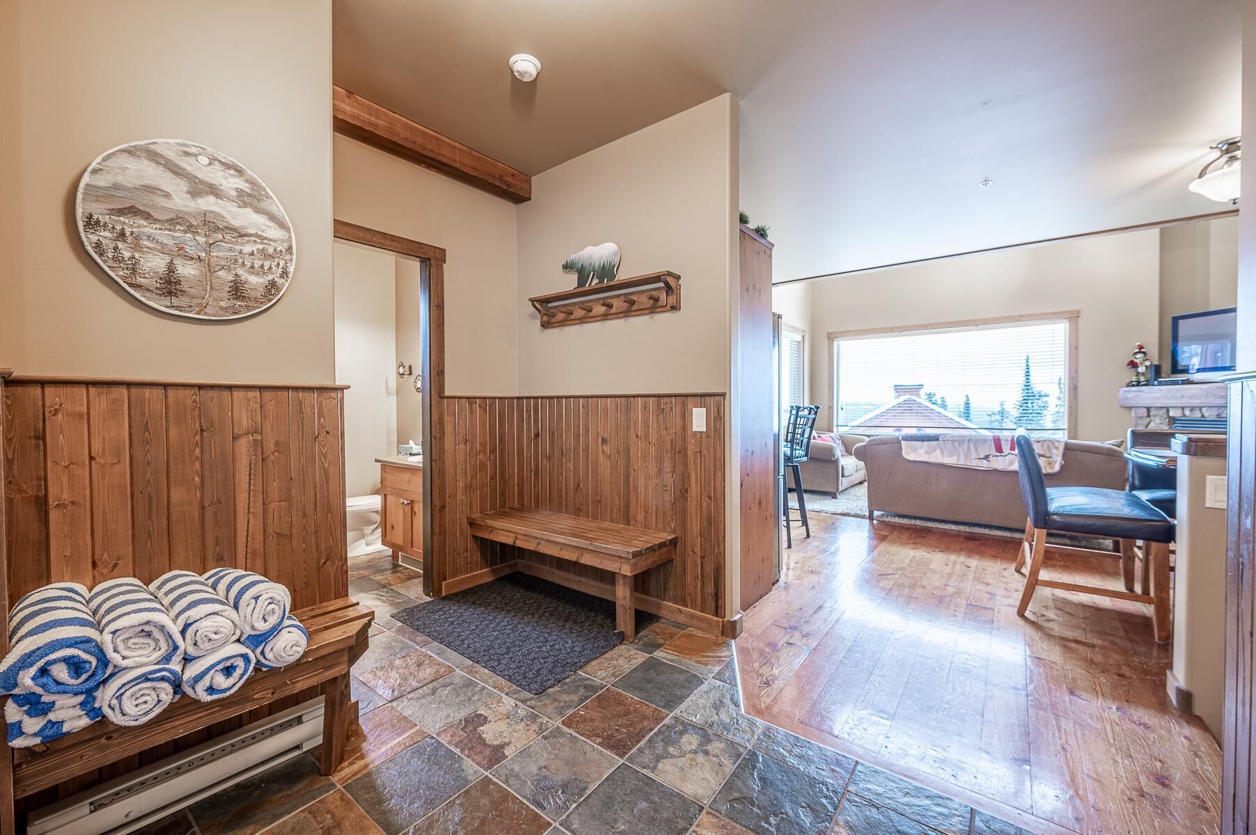A cozy interior with a wooden bench, a tiled floor, and a view of the outside through a window.