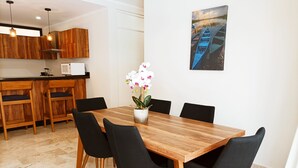 A dining area with a wooden table, black chairs, and a potted orchid. - VIVA 3BR 105-106 (Tulum)