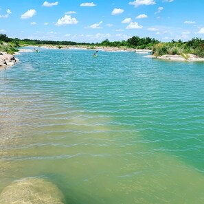 A river with clear water, a kayak, and a sandy beach. - The Rock Stack: Ruggedly luxurious 3 bedroom, 3 bathroom on the Llano River (Llano)