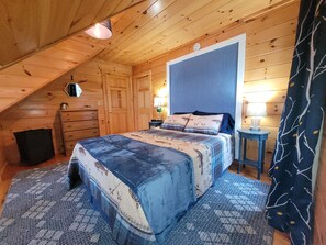 Una habitación acogedora con una cama, cómoda y una pequeña mesa con lámpara.