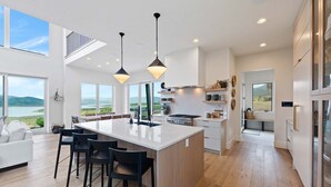 Een moderne keuken met een groot schiereiland, hanglampen en uitzicht op de omgeving.