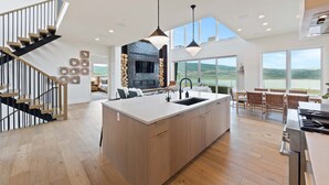 Een moderne keuken met een groot eiland, houten vloeren en uitzicht op de omgeving.