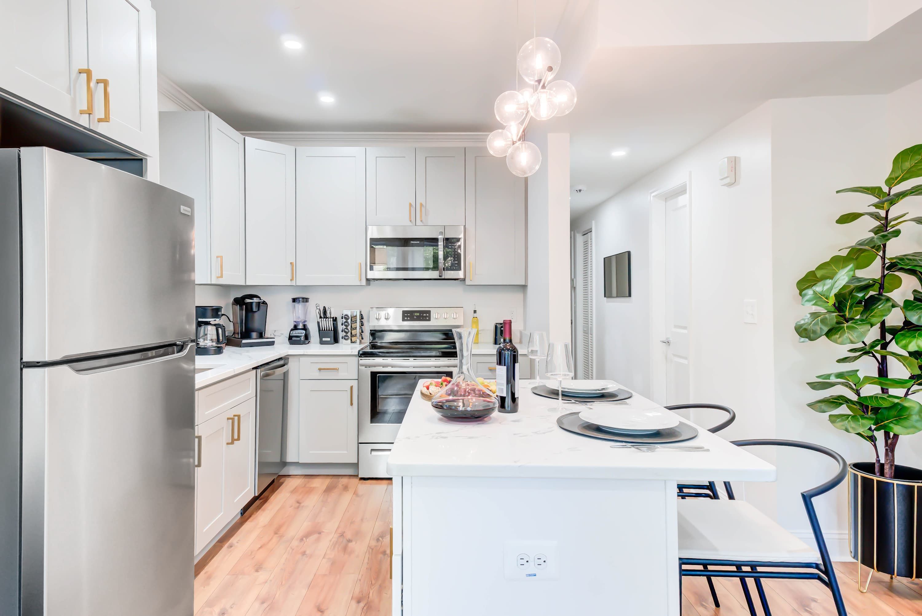 A modern kitchen with white cabinets, stainless appliances, and a central island with seating.